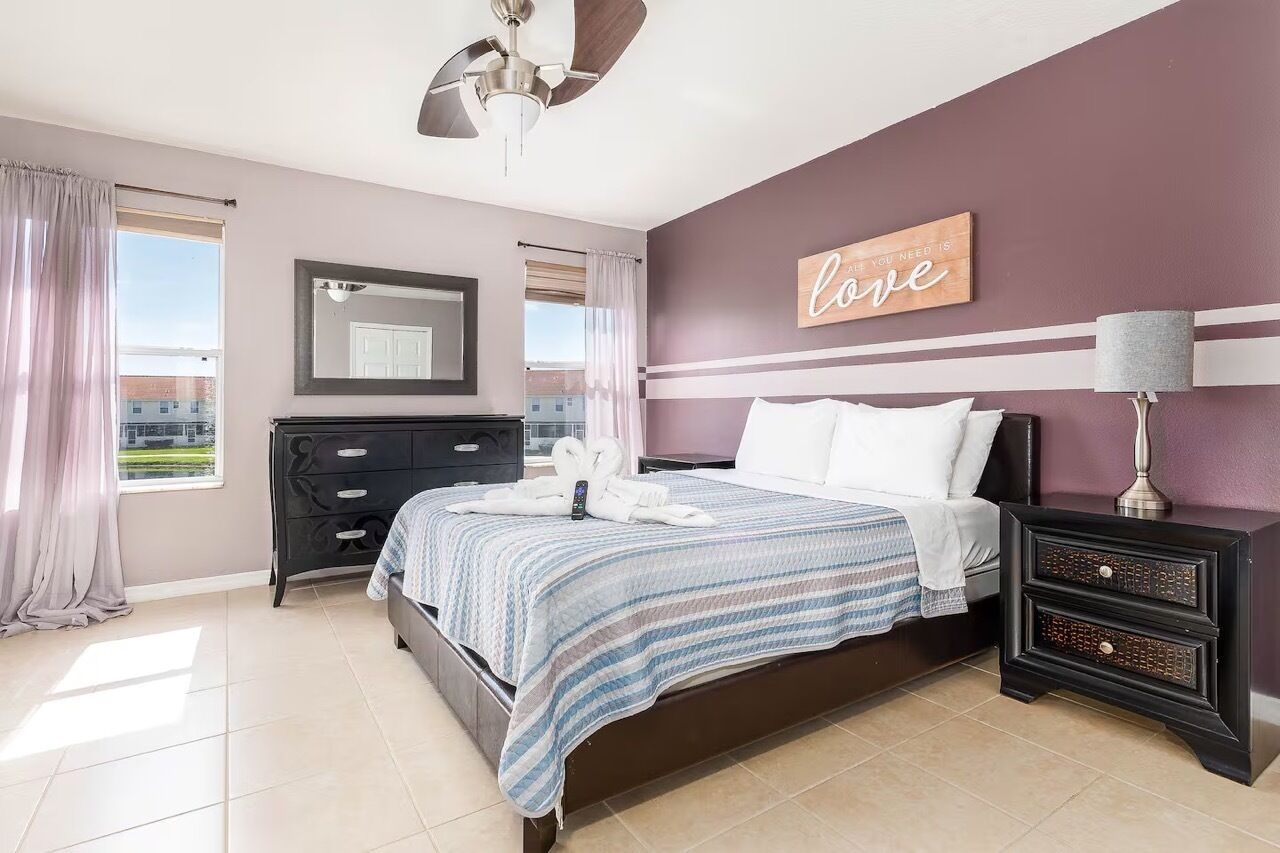 A bedroom with a bed, a nightstand, a dresser, a mirror, and a wall with a motivational quote.