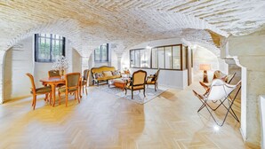 A spacious living room with a herringbone floor, a wooden dining set, and a sofa. - Les Voûtes de Bressey, historic prestige (Dijon)