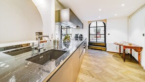A modern kitchen with a large island, built-in appliances, and a view through a window. - Les Voûtes de Bressey, historic prestige (Dijon)