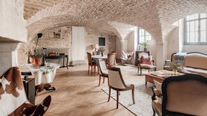 A spacious room with a high, textured ceiling, a dining area with a table and chairs, and a seating area with a sofa and armchairs. - Les Voûtes de Bressey, historic prestige (Dijon)