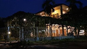 A house with a fenced yard, a well-lit entrance, and a visible balcony. - Bua Guest House (Medan)