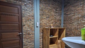 A room with a wooden wardrobe, a white sink, and a brick wall. - Bua Guest House (Medan)