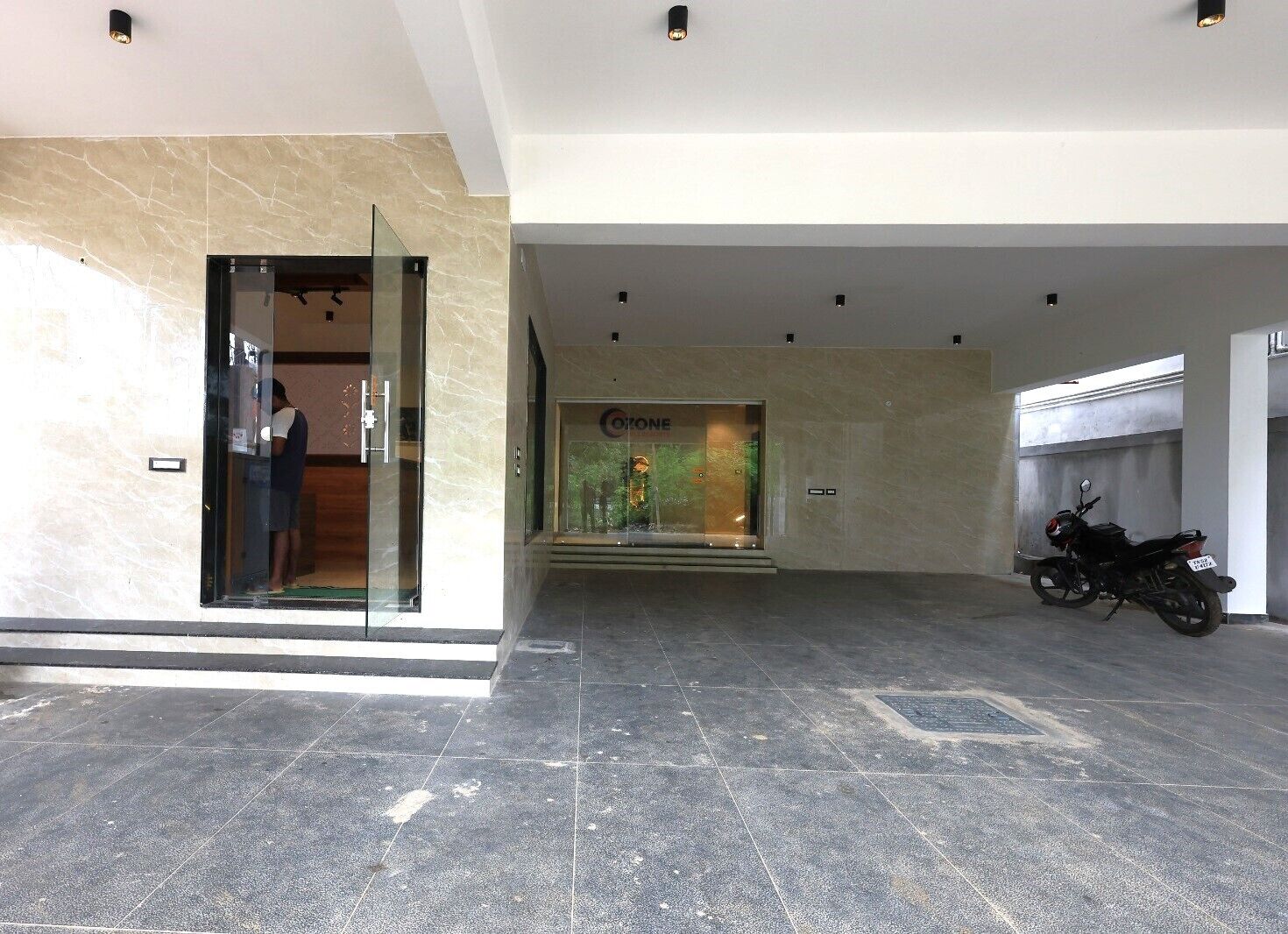A modern lobby with a glass entrance, a visible store named 'Cocoone', and a motorcycle parked inside.