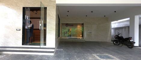 Un vestíbulo moderno con entrada de vidrio, una tienda a la vista llamada 'Cocoone' y una motocicleta estacionada adentro.
