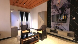 A modern living room with a wooden ceiling, a marble wall, a TV, and two wicker chairs. - Ozone Hill Resorts (Yercaud)