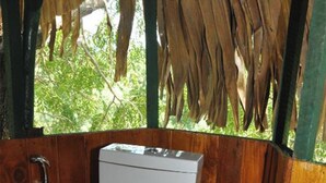 A compact, wooden bathroom with a white toilet, a shower area, and a small window.