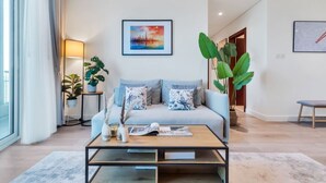 A modern living room with a light blue sofa, a coffee table, and two potted plants. - Family & Group Friendly,  Near Beach Metro & Marina (Dubai)