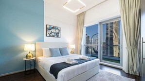 Ein modernes Hotelzimmer mit einem großen Bett, zwei Nachttischlampen, Blick auf die Stadt und einem geometrisch gemusterten Teppich.