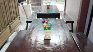 Una mesa de madera con un centro de mesa floral, bancos y vistas a un jardín.