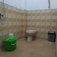 Un baño pequeño con inodoro, un cubo verde y un bote de basura.