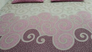 Una habitación pequeña con cama individual, colcha estampada y dos almohadas.