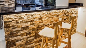 Cozinha moderna com backsplash de pedra, banquetas de madeira e eletrodomésticos de aço inoxidável.