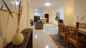 Uma sala de estar moderna com área de jantar, cozinha ao fundo e um espelho grande na parede.