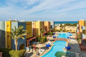 A resort with a swimming pool, palm trees, and a view of the sea. - Al Dora residence 3BR Hurghada (Hurghada)