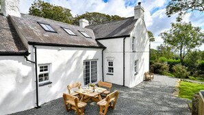 En hvid bygning med en grusbelagt terrasse og træmøbler.