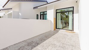 Una casa moderna con patio coperto, ampie porte scorrevoli in vetro e pavimento piastrellato.