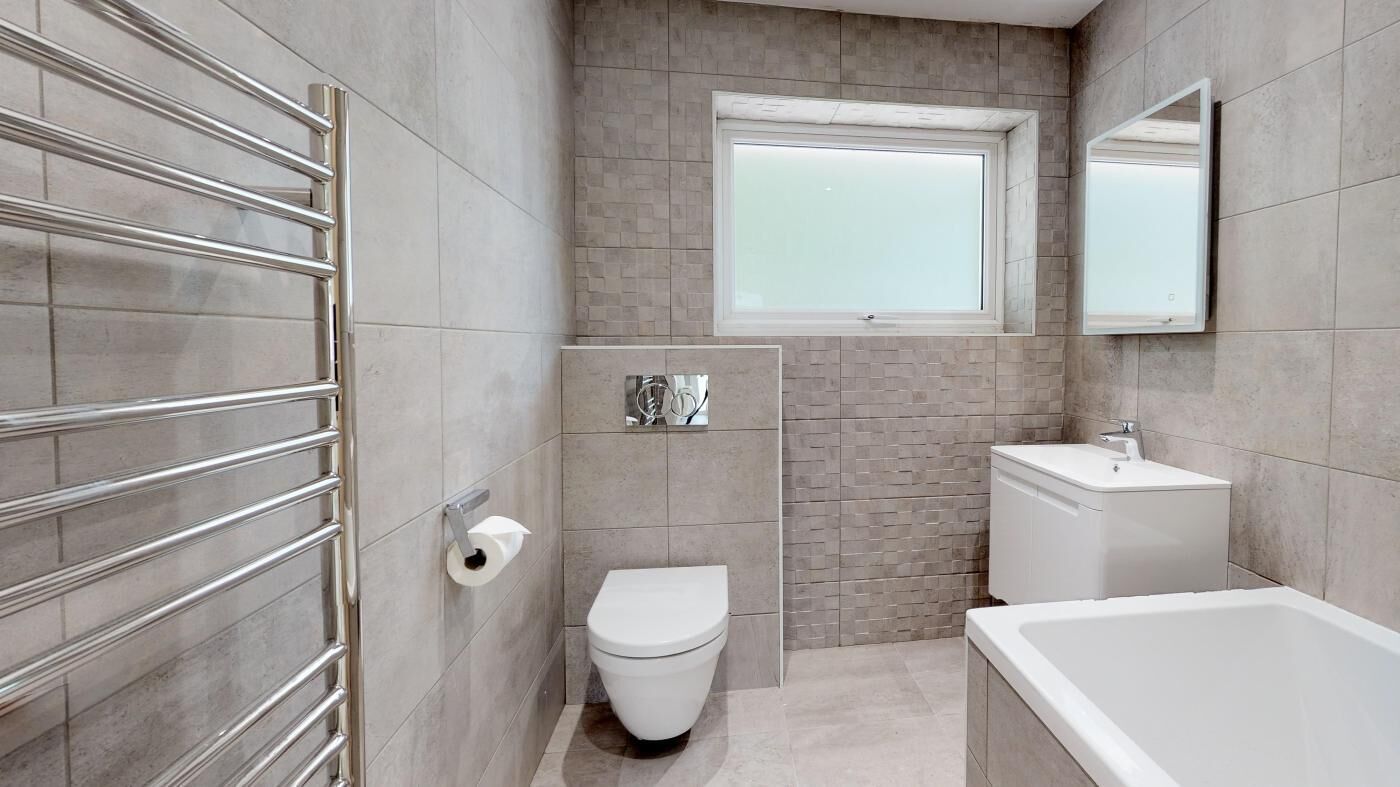 A modern bathroom with a toilet, sink, and bathtub.