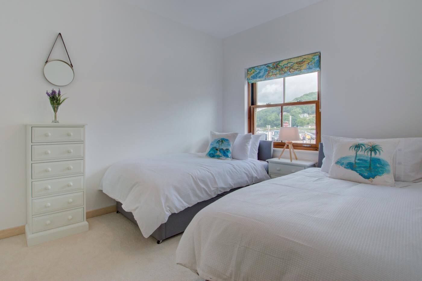 Une chambre avec deux lits, une commode, une fenêtre donnant sur un beau paysage et une carte accrochée au mur.
