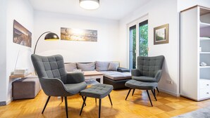 Een moderne woonkamer met een bank, twee fauteuils, een salontafel en een boekenkast.