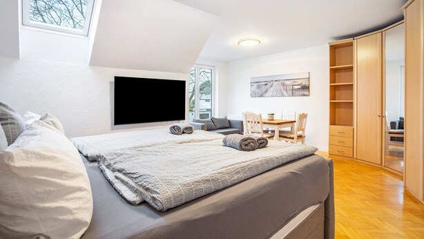 Een slaapkamer met een bed, een televisie, een bureau en een kledingkast.