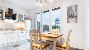 Een moderne keuken met witte kastjes, een eettafel met stoelen en een groot raam.