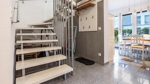 Een modern interieur met een trap, een eethoek en uitzicht door grote ramen.