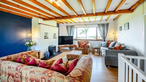 Una sala de estar acogedora con techo de madera, un televisor grande y asientos cómodos.