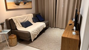 A modern living room with a sofa, a coffee table, a TV stand, and a painting of boats on the wall. - Beachfront apartment, best stretch of beach. (Tamandaré)