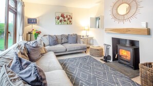 Un salon chaleureux avec un canapé, une cheminée, un tapis et un tableau accroché au mur.