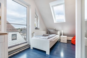 Ein Schlafzimmer mit großem Fenster, einem Bett, einem Nachttisch und einem roten Sitzsack.