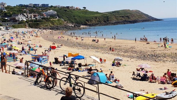 A crowded beach with people sunbathing and swimming, tents, and bicycles. - 4 Bed in Mumbles (oc-hh53) (The Mumbles)
