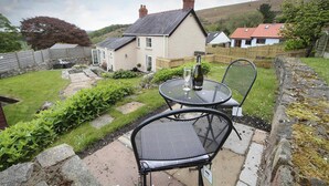 A house with a garden, a patio with chairs, and a bottle of wine on the table. - 2 Bed in Llanmadoc (oc-hh469) (Llanmadoc)