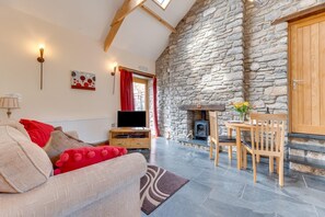 Ein gemütliches Wohnzimmer mit Steinwand, Kamin, Fernseher und Essbereich mit Stühlen.