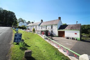 A traditional building with a grassy area in front, a signboard advertising food service, and a flag display.