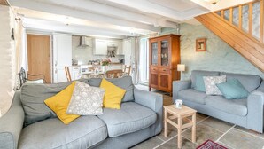 Een gezellige woonkamer met twee grijze banken, een houten kast en een kleine houten tafel.