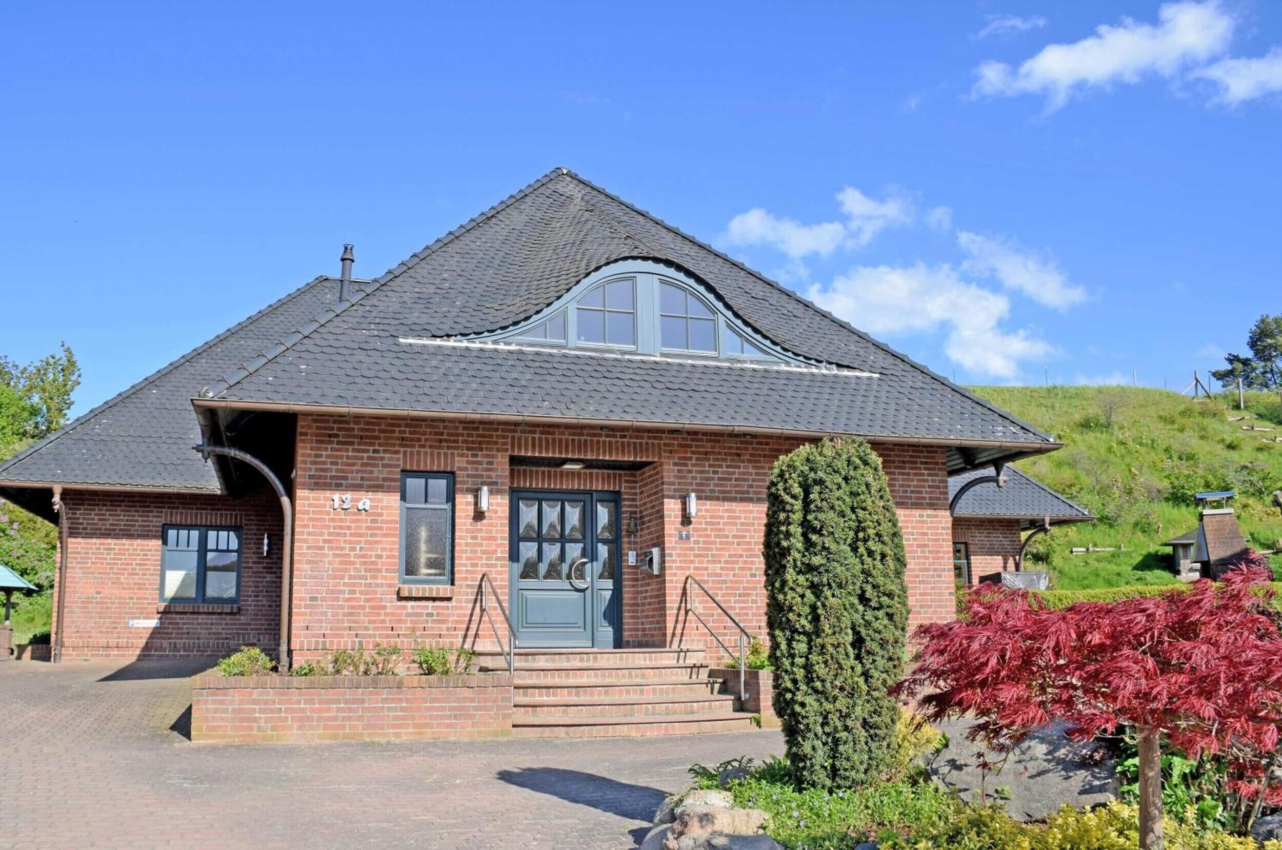 A brick house with a dark blue door, a small porch, and a number '134' on the front.