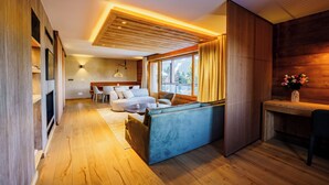 Un interior moderno con suelo de madera, un sofá, una mesa de comedor y un televisor.