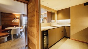 Una cocina moderna con detalles de madera, una zona de comedor con una mesa redonda y sillas, y un horno empotrado.