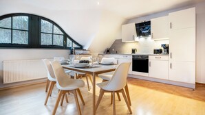 A modern kitchen with white cabinetry, a dining table with chairs, and a large window. - Apartment 'Ferienwohnung 5 Seebrücke' with Lake View, Private Terrace and Wi-Fi (Sellin)