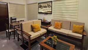 Un salon avec un ventilateur de plafond, un ensemble de canapés, une table basse et un tableau accroché au mur.