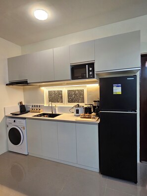 A modern kitchen with a washing machine, microwave, refrigerator, and a sink. - Cozy 3-bedroom house in charming Dauis, Panglao Island, Bohol (Dauis)