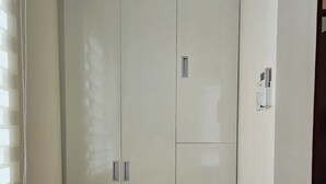 Une pièce dotée d’une grande armoire, d’une petite fenêtre avec des stores et d’un thermostat fixé au mur.