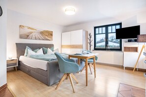 Une chambre moderne avec un lit, une table de chevet et une fenêtre donnant sur un beau paysage.