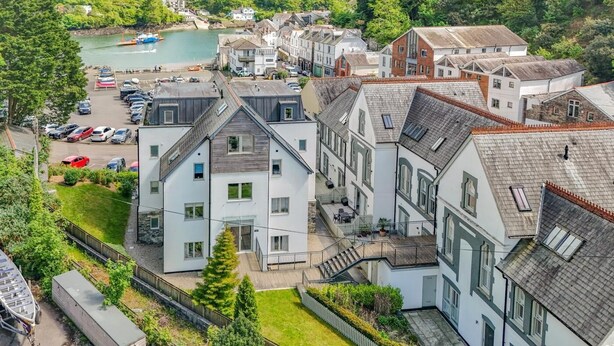 Ett bostadsområde med flerfamiljshus, en småbåtshamn och en sluttning som bildar bakgrund.