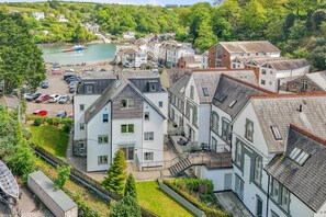 A residential area with multi-story houses, a marina with boats, and a hillside backdrop. - 2 Bed in Fowey (oc-p00677) (Fowey)
