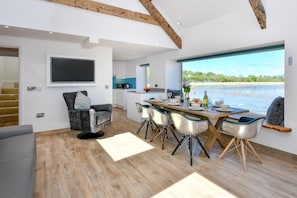 Un intérieur moderne comprenant un coin repas, une cuisine et une grande fenêtre donnant sur un plan d’eau.
