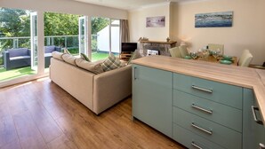 A modern kitchen with a large island, a sofa with cushions, and a dining area with a table set for two. - 2 Bed in Llanbedrog (oc-5glyny) (Llanbedrog)