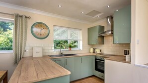 A modern kitchen with a wooden countertop, a built-in oven, and a window with blinds. - 2 Bed in Llanbedrog (oc-5glyny) (Llanbedrog)