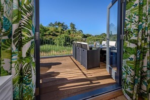 A deck with a table and chairs, overlooking a garden with a metal fence. - 3 Bed in Abersoch (oc-9penyb) (Abersoch)