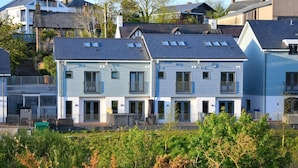 Une rangée de maisons de ville à deux étages, dotées de balcons, d’un jardin clos et offrant une vue sur les maisons voisines.